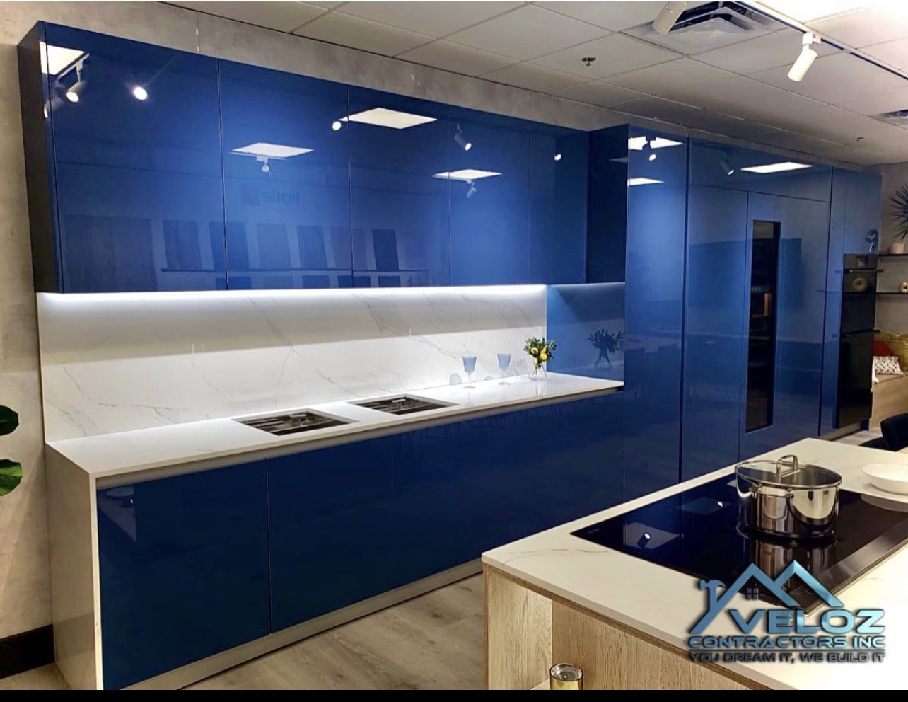 Modern blue kitchen remodel by Veloz Contractors featuring high-gloss cabinetry, marble countertops, and under-cabinet LED lighting