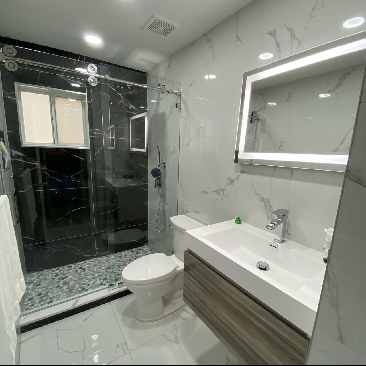 Modern bathroom with black and white marble tile, glass shower door