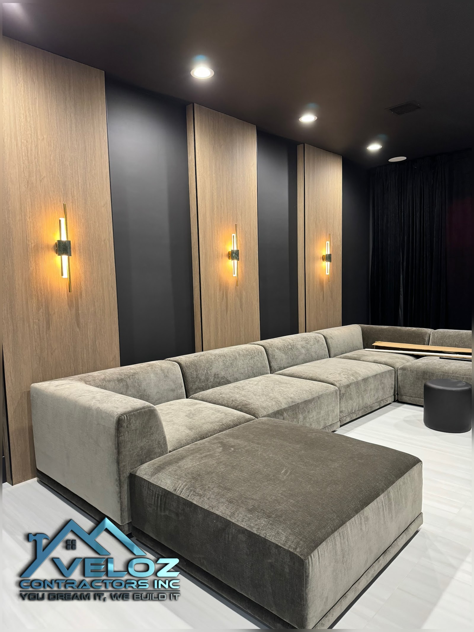 Modern media room with accent wall, wood slats, and gold sconces