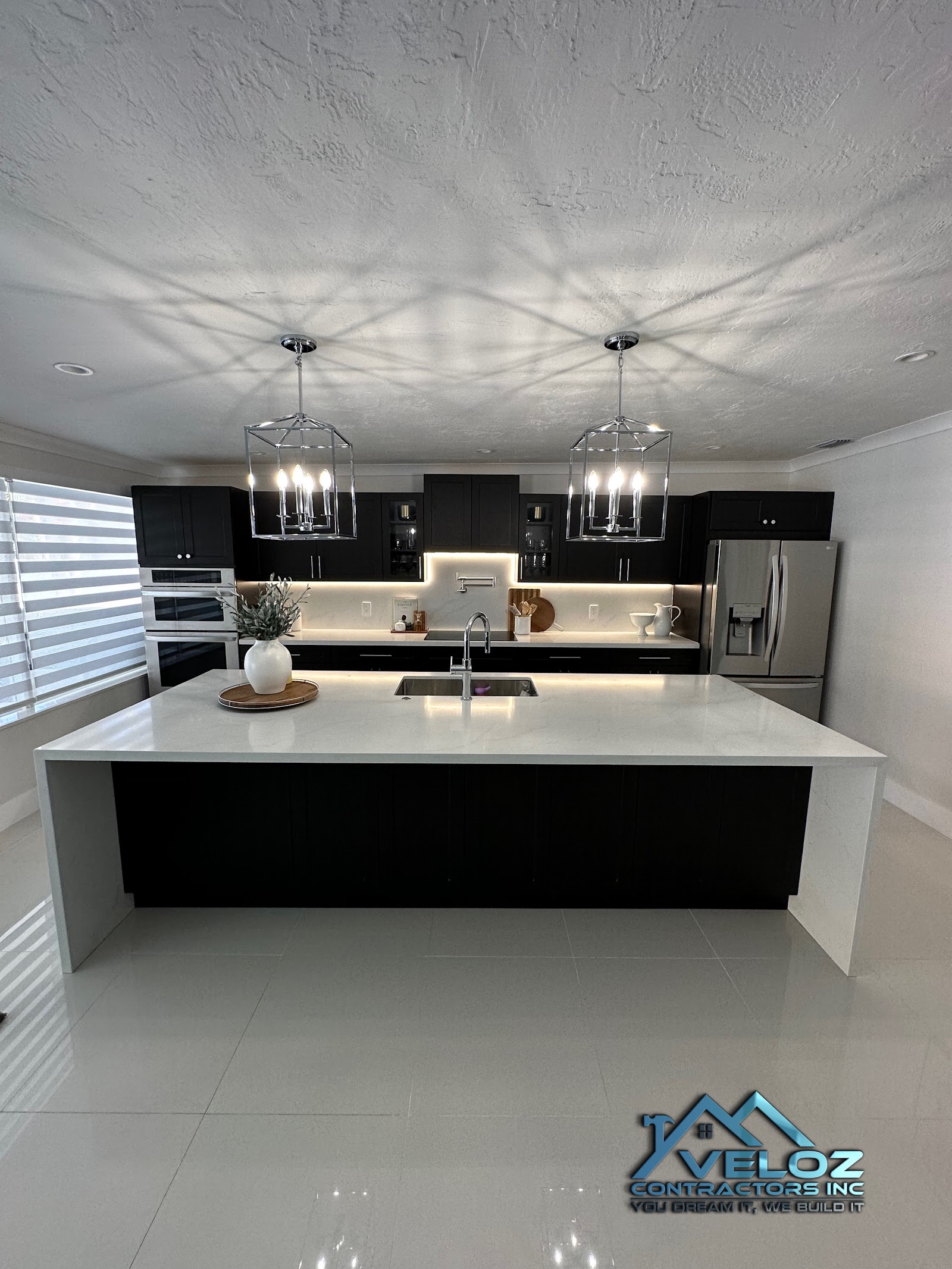 Modern kitchen with dark cabinetry, waterfall island, and pendant lighting
